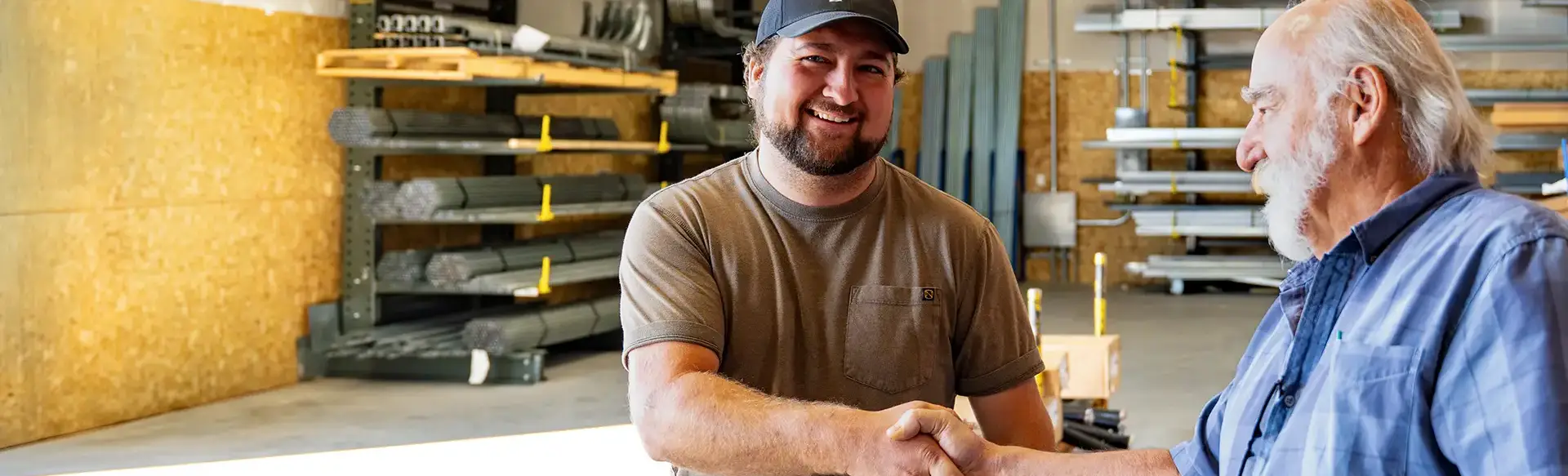 A Western States Garage Door Supply Inc employee shakes hands with a man, standing in the warehouse.