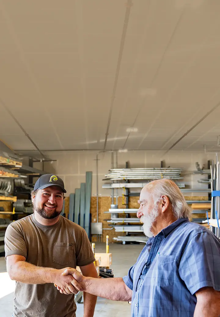 A Western States Garage Door Supply Inc employee shakes hands with a man, standing in the warehouse.