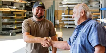 Two men shake hands in Western States Garage Door Supply warehouse.